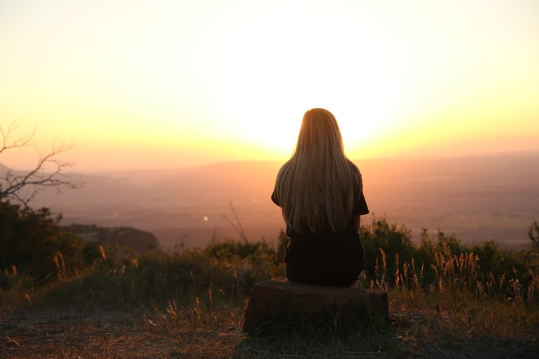 Girl sitting looking at sunset