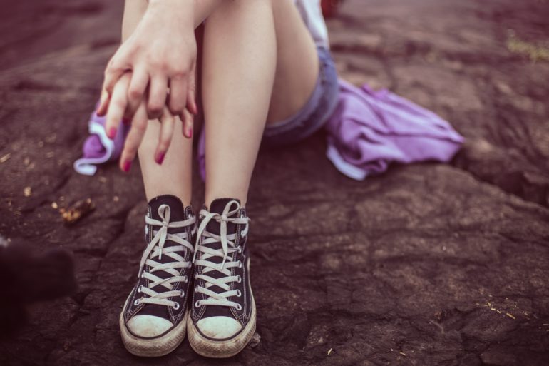 Girl sitting on rock with hands interlocked