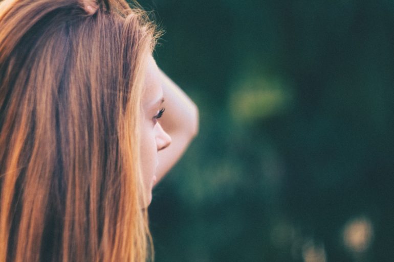 Teen girl holding head and looking out of frame