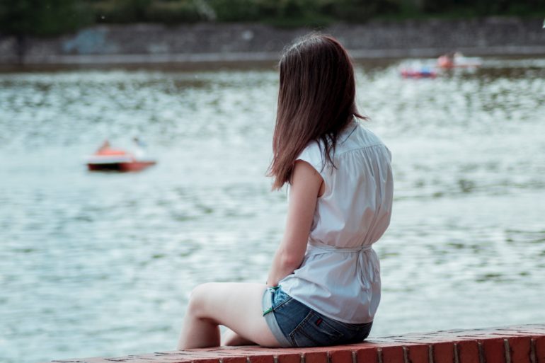 teen girl sitting on dock looking out at water